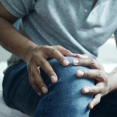 Close-up of a person holding a painful knee joint, showcasing joint and limb care services provided by a Sheffield chiropractor.